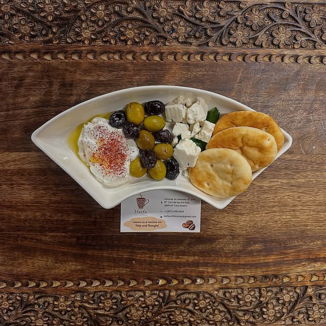 A plated spread photographed on a carved wooden table at Haifa Coffeehouse